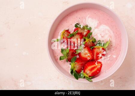 Frühstück mit Müsli, Kokosnuss und Erdbeer Smoothie in einer Schüssel auf einem rosa hellen Hintergrund. Frühling Diät-Menü.Draufsicht. Stockfoto