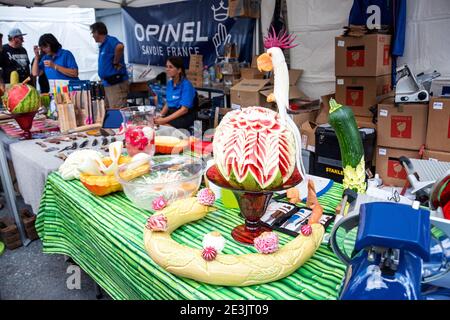 BOURG-SAINT-MAURICE, FRANKREICH - 19. AUGUST 2018: Opinel Messer Firmenstand mit schönen Gemüse-und Obst Schnitzereien im traditionellen Agricul Stockfoto