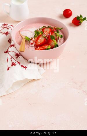 Frühstück mit Müsli, Kokosnuss und Erdbeer Smoothie in einer Schüssel auf einem rosa hellen Hintergrund. Frühling Diät-Menü.Draufsicht. Stockfoto