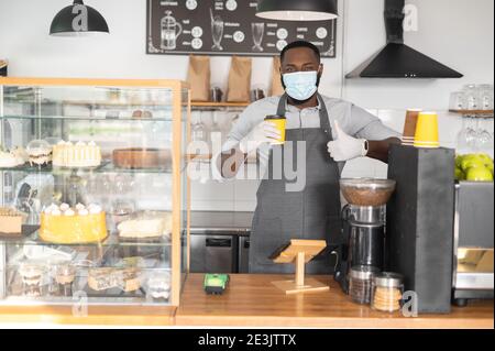 Ein afrikanischer Kellner in einer medizinischen Maske Stockfoto