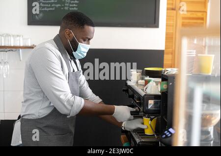 Ein afrikanischer Kellner in einer medizinischen Maske Stockfoto