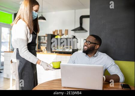 Eine Kellnerin in einer medizinischen Maske Stockfoto