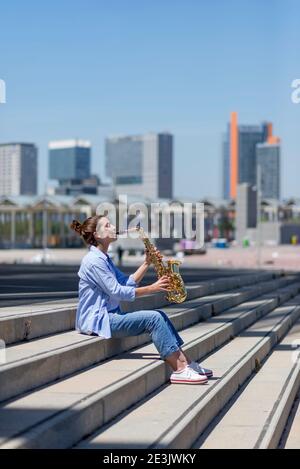 Frau mit Pferdeschwanz spielt Saxophon, während sie im Freien steht Stockfoto