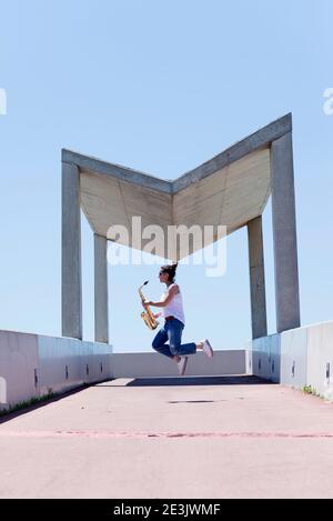 Frau mit Pferdeschwanz spielt Saxophon, während sie im Freien steht Stockfoto