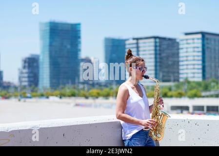 Frau mit Pferdeschwanz spielt Saxophon, während sie im Freien steht Stockfoto