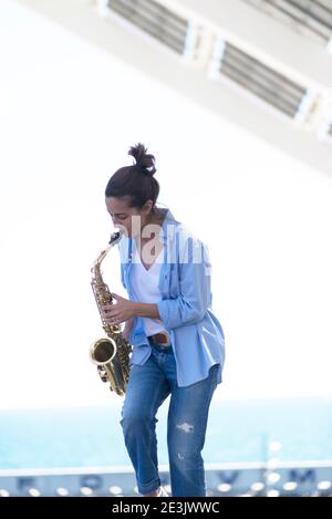 Frau mit Pferdeschwanz spielt Saxophon, während sie im Freien steht Stockfoto