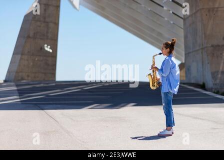 Frau mit Pferdeschwanz spielt Saxophon, während sie im Freien steht Stockfoto