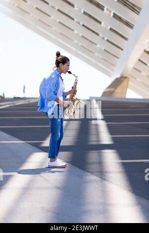 Frau mit Pferdeschwanz spielt Saxophon, während sie im Freien steht Stockfoto