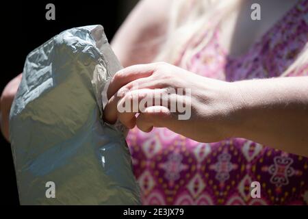 Nahaufnahme der Hände einer Frau, die weiße, gepolsterte Post öffnet Paket Stockfoto