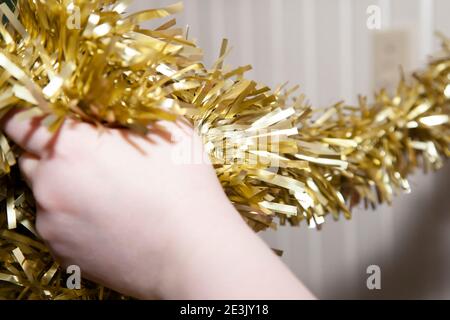 Frau, die goldenes Lametta auf einen Weihnachtsbaum legt Stockfoto