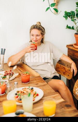 Junge Frau trinkt kalte Limonade, während sie im Café sitzt Stockfoto