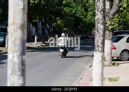 Schnelle Lieferung von Lebensmitteln auf Motorroller in der Stadt. Dieses Bild kann verwendet werden, um die Lieferung von Lebensmitteln in der Stadt zu bewerben oder zu beschreiben. Stockfoto