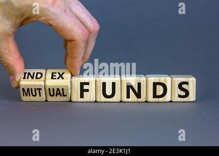 Index vs. Investmentfonds-Symbol. Geschäftsmann dreht einen Würfel und ändert die Wörter "Mutual Funds" in "Index Funds. Schöner orangefarbener Hintergrund, Kopierbereich. Busi Stockfoto