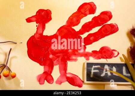 Rote Hand-pute auf Vanille-Baupapier mit orangen Beeren, Herbstlaub und einem 'FALL'-Zeichen Stockfoto