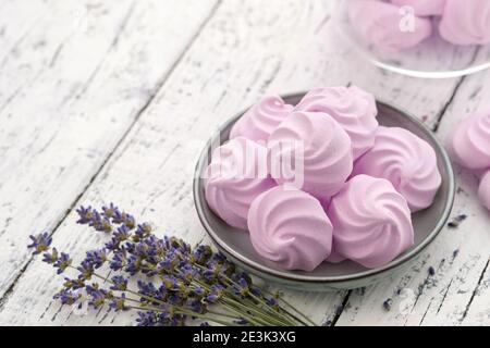 Hausgemachte milde Lavendel Marshmallows auf einem blauen Teller und Lavendelblüten auf Küchentisch. Glas Glas von natürlichen Marshmallows auf dem Hintergrund. Stockfoto