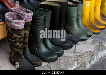 Gummistiefel in verschiedenen Farben auf den Regalen des Straßenmarktes. Selektiver Fokus Stockfoto