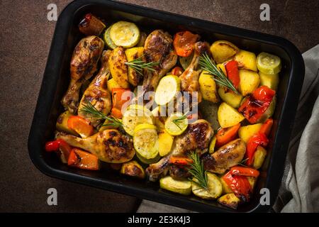 Gebackenes Huhn mit Gemüse, das im Ofen beim Backblech zubereitet wird. Stockfoto