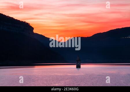 Landschaft des Sauer Sumpfes mit seiner Kirche. Sonnenuntergang oder Sonnenaufgang mit warmen und orangen Farben im Sau Reservoir. Tourismus in Osona, Barcelona, Catalonia, Sp Stockfoto