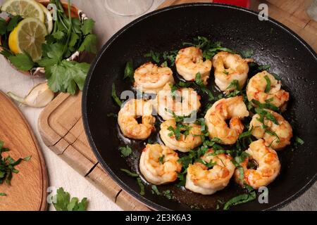 Geröstete Garnelen mit Knoblauch und Kräutern auf der Pfanne. Nahaufnahme. Meeresfrüchte, Schalentiere. Stockfoto