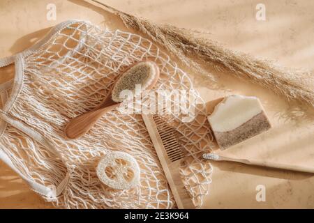 Zero Waste Bad Accessoires Haarbürste, Bambus Zahnbürste, Loofah und Naturseife in wiederverwendbaren Einkaufstasche auf beigem Hintergrund. Draufsicht. Vintage Stockfoto