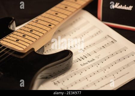Nahaufnahme von E-Gitarre und Musikbuch mit einem Marshallverstärker im Hintergrund. Üben, komponieren oder produzieren Sie Rockmusik. Stockfoto
