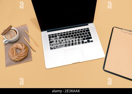 Laptop, Kuchen, Tasse Tee oder Glühwein und Lebenslauf Blatt auf dem pastellorange Tisch, Draufsicht. Stockfoto