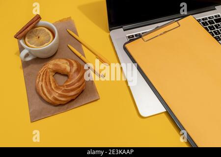 Laptop, Kuchen, Tasse Tee und Lebenslauf Blatt auf der Fortuna Gold Gelb Farbe Hintergrund, Draufsicht. Stockfoto