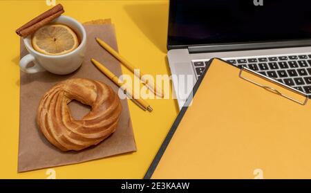 Laptop, Kuchen, Tasse Tee und Lebenslauf Blatt auf der Fortuna Gold Gelb Farbe Hintergrund, Draufsicht. Stockfoto