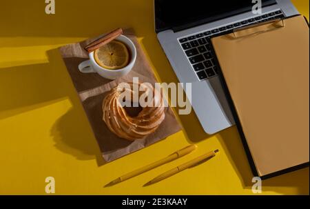 Hände Halten Lebenslauf Blatt in der Nähe Laptop, Kuchen und Tasse Tee auf dem Fortuna Gold Gelb Farbe Hintergrund, Draufsicht. Stockfoto