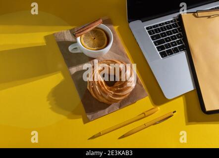 Hände Halten Lebenslauf Blatt in der Nähe Laptop, Kuchen und Tasse Tee auf dem Fortuna Gold Gelb Farbe Hintergrund, Draufsicht. Stockfoto