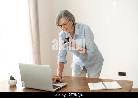 Reife Geschäftsfrau, die eine Sprachnachricht aufzeichnet Stockfoto