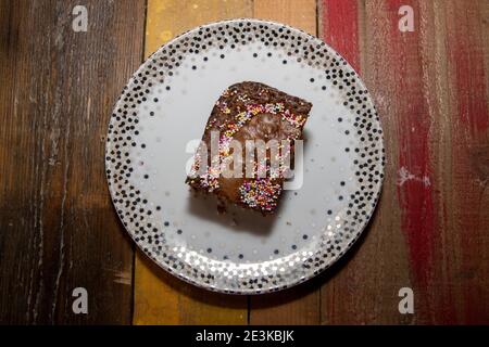 Eine leckere Brownie-Tortenscheibe aus Schokolade mit Streuseln Eine hölzerne Küchenarbeitsfläche Stockfoto