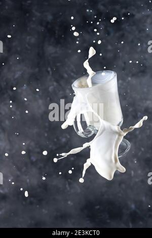 Spritzer Milch aus dem Glas auf einem grauen Hintergrund. Levitation. Stockfoto