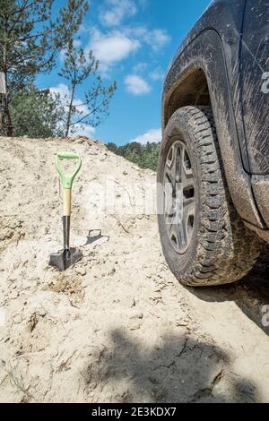 Sand Offroad-Konzept. Schaufel in der Nähe suv Autorad. Nahaufnahme Stockfoto