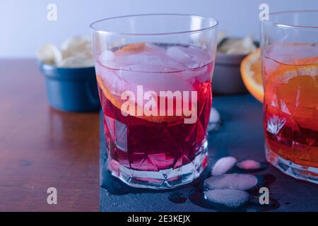 Zwei Spritzer mit einigen Chips auf dem Tisch bereit für den Aperitif, der rote wird mit Campari gemischt. Ein Sprtiz wird mit aperol und einer mit Campar gemischt Stockfoto