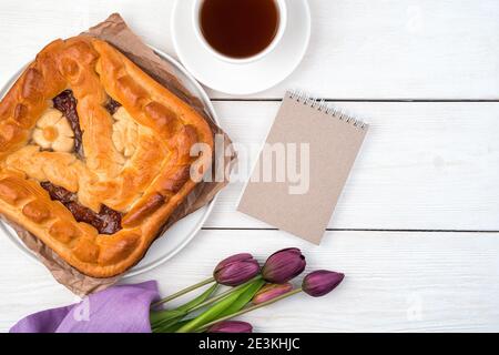 Apfelkuchen, Notizblock und Tulpen auf hellem Hintergrund. Draufsicht, mit Platz zum Kopieren. Stockfoto