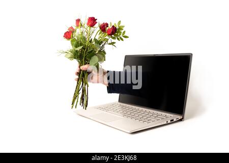 Hand eines Mannes mit einem Strauß roter Rosen aus einem Laptop-Bildschirm, digitale Liebe am Valentinstag mit sozialer Distanz während covid-19 Pandemie, Stockfoto