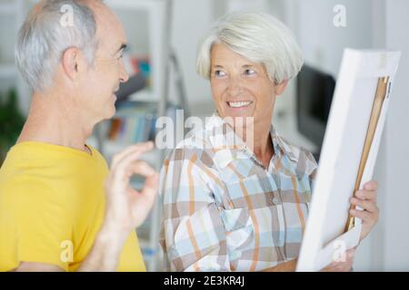Ältere Paar Blick auf Bilderrahmen in neue Wohnung Stockfoto