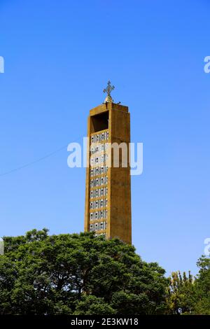 Der majestätische Glockenturm der Kirche unserer Lieben Frau Maria von Zion in Aksum, Äthiopien mit seinem verzierten Axumit Kreuz durchdringt einen tiefblauen Himmel. Stockfoto