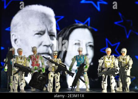 In dieser Fototaparie sehen wir die Spielzeugsoldaten vor der Werbung für die Amtseinführung des Präsidenten mit dem Bild des designierten US-Präsidenten Joe Biden und des designierten US-Vizepräsidenten Kamala Harris auf einem Bildschirm im Hintergrund. Stockfoto