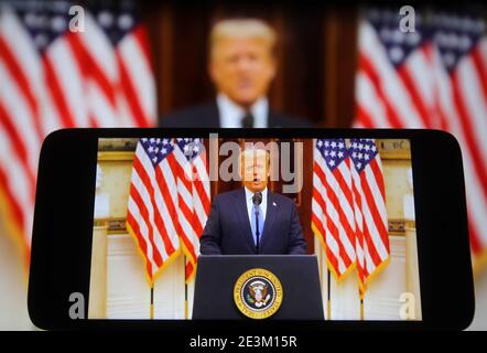 In dieser Fototafel spricht US-Präsident Donald Trump bei seiner Abschiedsrede während seines letzten Tages im Amt auf einem Fragment von youtube-Video, das auf einem Mobiltelefon und einem pc-Bildschirm angezeigt wird. Stockfoto