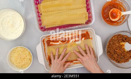 Rindfleisch Lasagne Schritt für Schritt Rezept. Lasagne zusammenbauen. Schicht Lasagne Nudeln. Frau Hände, flach liegen Stockfoto