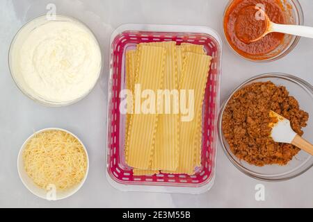 Gekochte Lasagne Nudeln, Marinara-Sauce, Hackfleisch, Käse in Schalen. Zutaten für Rindfleisch Lasagne Rezept close up auf Küchentisch, flach legen. Stockfoto