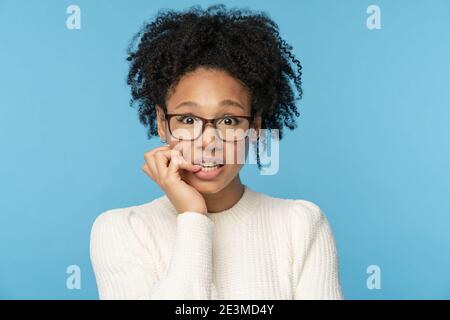 Schüchtern umständlich Afro Frau tragen Brille beißen Finger Gefühl verlegen, verwirrt und nervös. Studio. Stockfoto