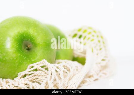 Grüne Äpfel in Öko-Netzbeutel auf weißem Küchentisch. Markteinkäufe. Lebensmittel- und Umweltkonzept. Keine Verschwendung. Nahaufnahme. Banner. Stockfoto