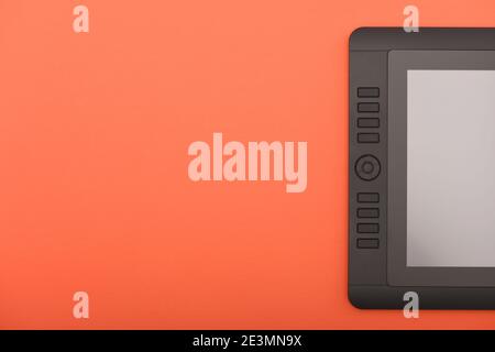 Grafikmonitor auf orangefarbener Farbtabelle. Schwarzer Tablet-Computer mit leerem Bildschirm. Hochauflösendes Foto. Volle Schärfentiefe. Arbeitsumgebung concep Stockfoto