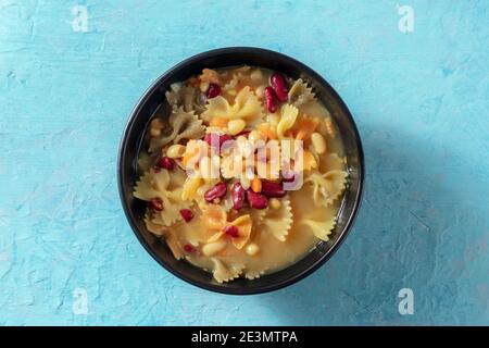 Vegane Suppe mit Pasta und Bohnen, von oben auf blauem Hintergrund geschossen Stockfoto