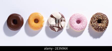 Flache Lay-Komposition mit gemischten Donuts auf weißem Hintergrund. Stockfoto