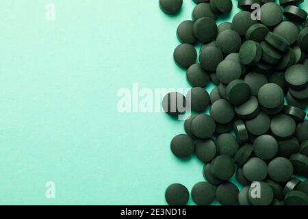 Dunkelgrüne Spirulina-Tabletten, die sich über eine frische Minze-Basis verteilen, mit Platz für Text, ein Spirulina-Superfood-Nahrungsergänzungsmittel für Wohlbefinden und Spirulina-Entgiftung Stockfoto