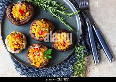 Gebackene gefüllte portobello-Pilze mit Bulgur-Pilaf und gehacktem Gemüse. Leckeres und nahrhaftes vegetarisches Gericht. Steinhintergrund, selektiver FOC Stockfoto